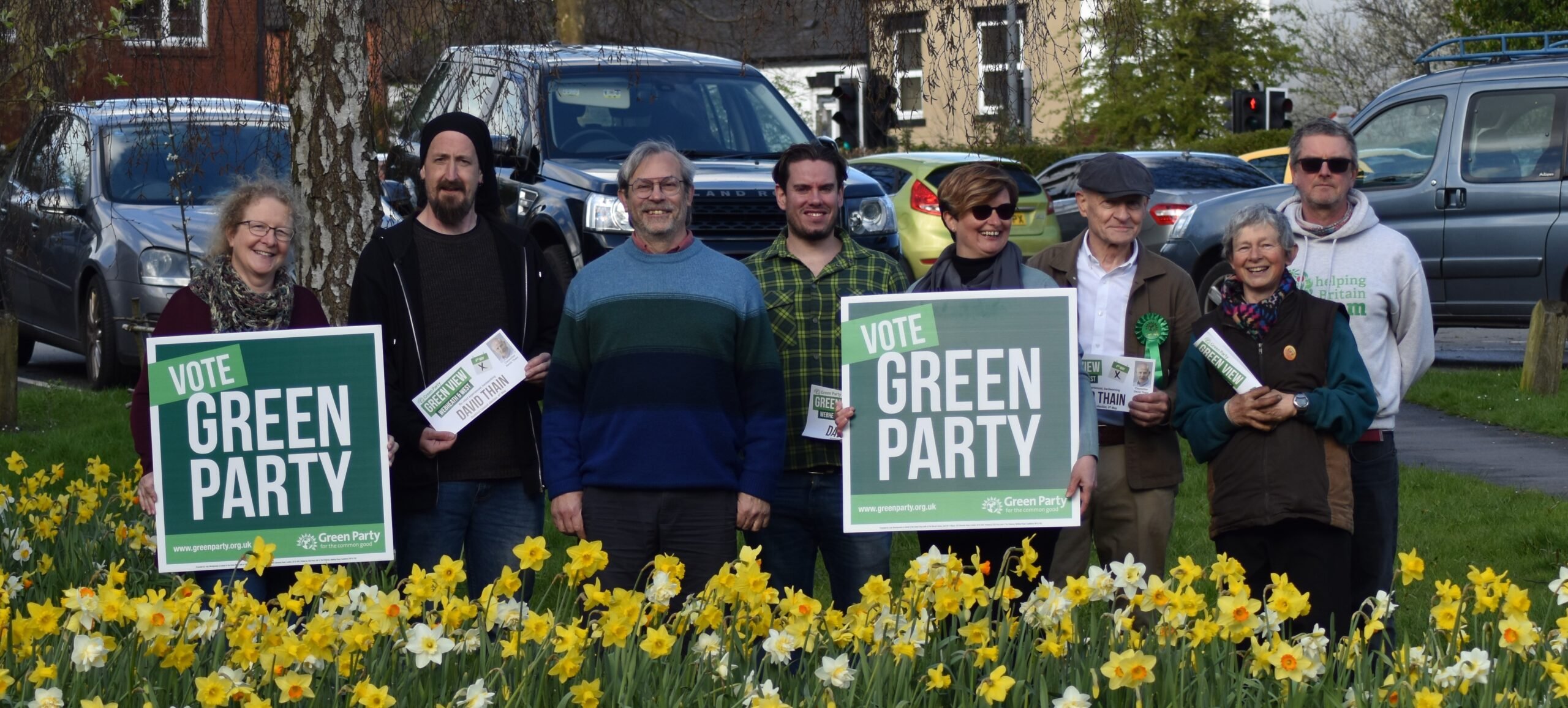 local green party members holding placards with daffodils in front